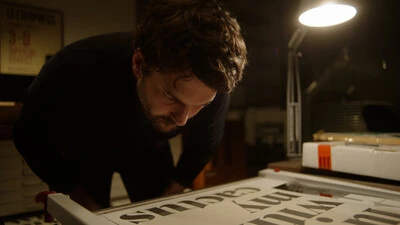 A still image from Foundry Stories showing Rene Bieder in his studio looking at type.